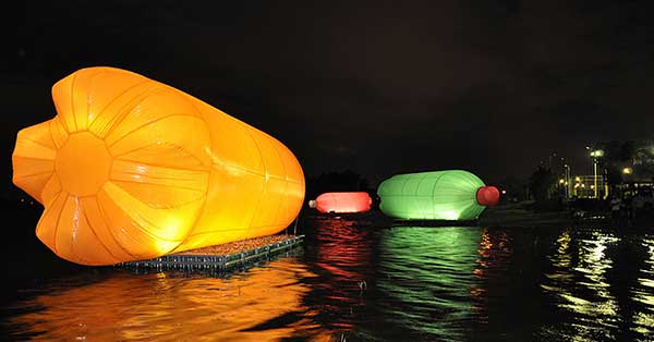 Três garrafas pets monumentais iluminadas flutuando sobre o rio Tietê em exposição promovida pelo Itaucultural em 2008