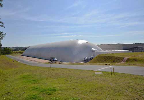 Tenda tipo cobertura pneumática temporária utilizada como armazém inflável na cor branca instalada sobre pavimento de asfáltico utilizada para armazenagem de fertilizante a granel.